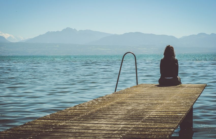 vrouw zit op een steiger aan het water